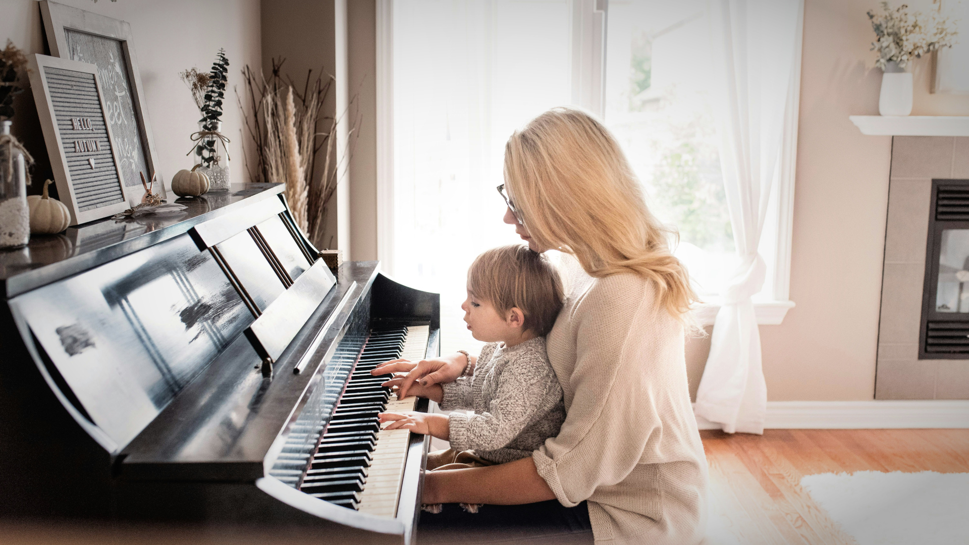 Musiklehrerin unterrichtet ein Kind am Klavier in heller, warmer Atmosphäre