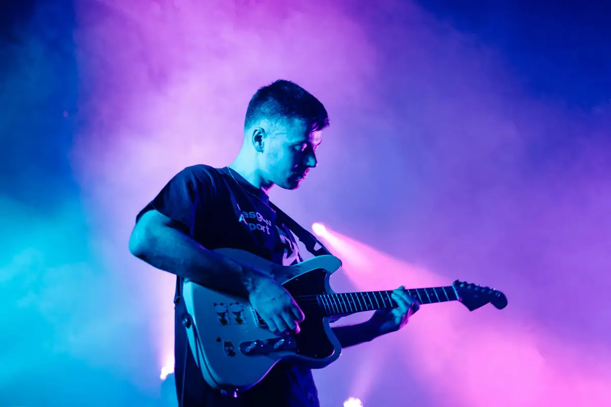 Gitarrist auf der Bühne in violett-blaulichem Licht — Release-Vorbereitung für Musiker
